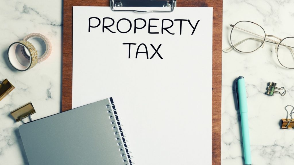 Clipboard labeled Property Tax with pens and glasses on a desk