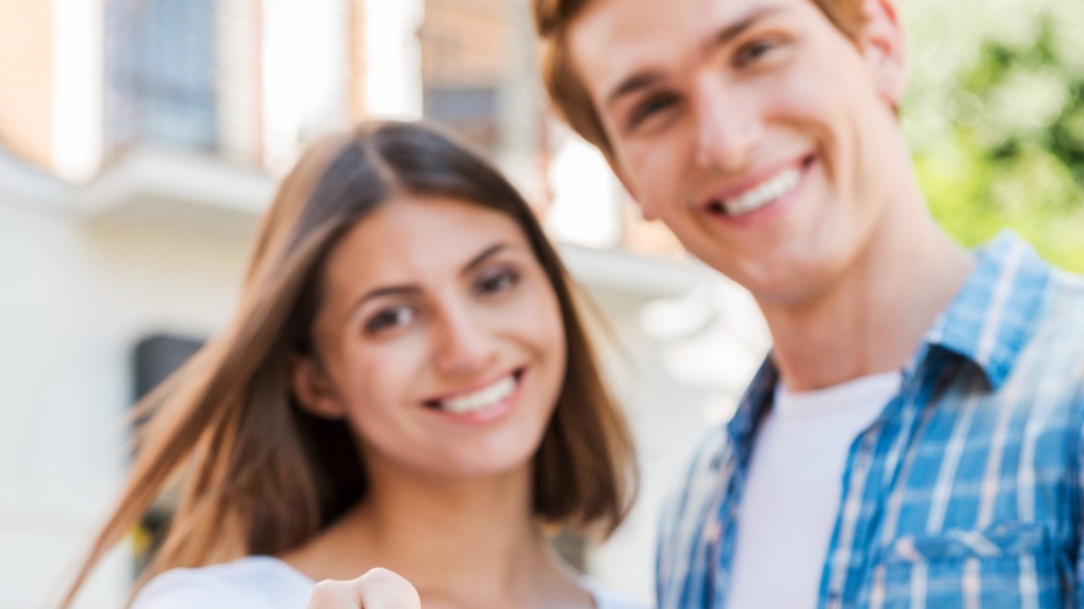 Smiling couple standing outside their new home