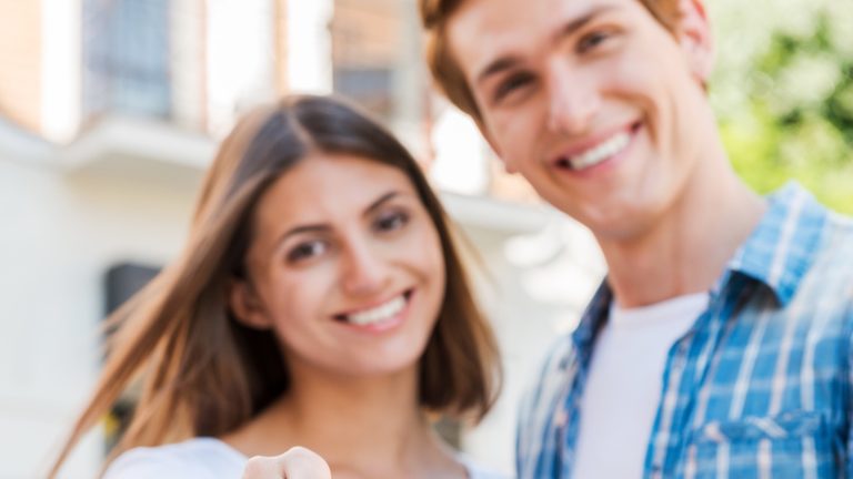 Smiling couple standing outside their new home